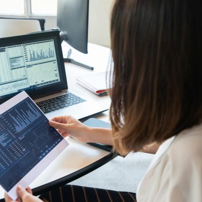 pexels-photo-6248957-6248957 A professional woman analyzes financial charts on a laptop and paper for business insights.